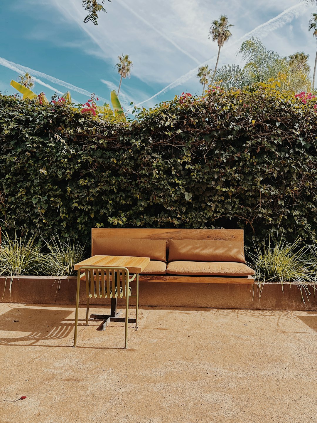 Wooden bench and metal table sit beside an ivy wall.